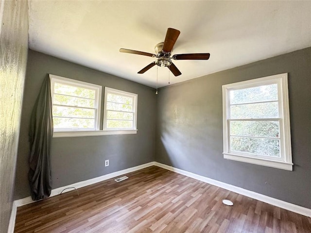 empty room featuring visible vents, baseboards, and wood finished floors