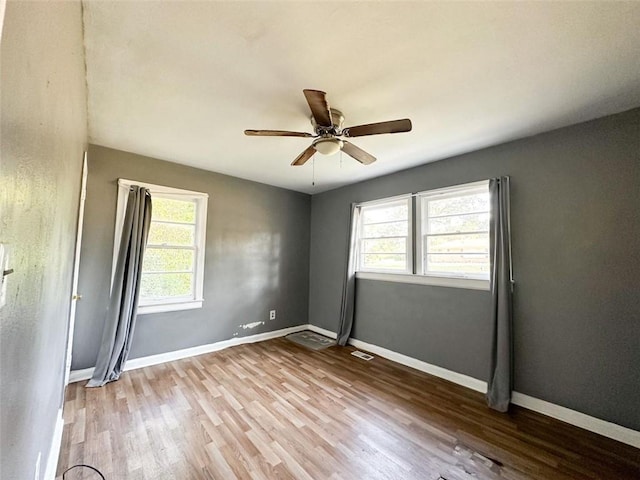 unfurnished room featuring visible vents, wood finished floors, a ceiling fan, and baseboards