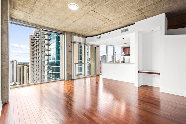 unfurnished room featuring hardwood / wood-style flooring, baseboards, and floor to ceiling windows