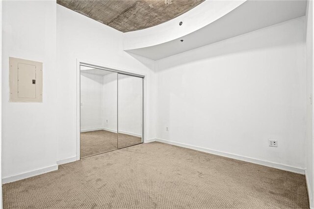 unfurnished bedroom featuring electric panel, carpet flooring, a closet, and baseboards