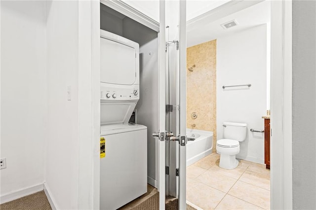 full bathroom with stacked washing machine and dryer, toilet, tile patterned flooring, shower / bath combination, and baseboards