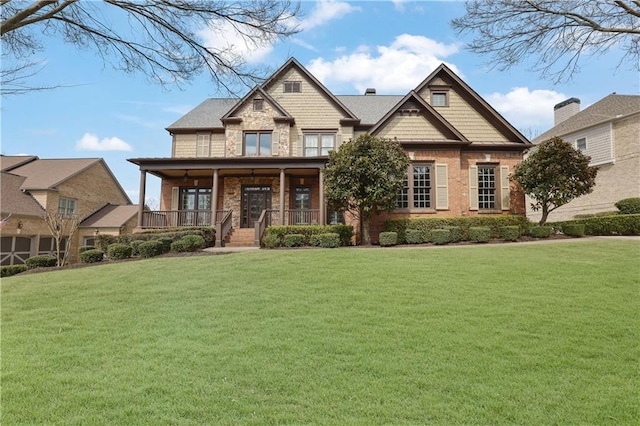 craftsman-style house featuring a front lawn, covered porch, and stone siding