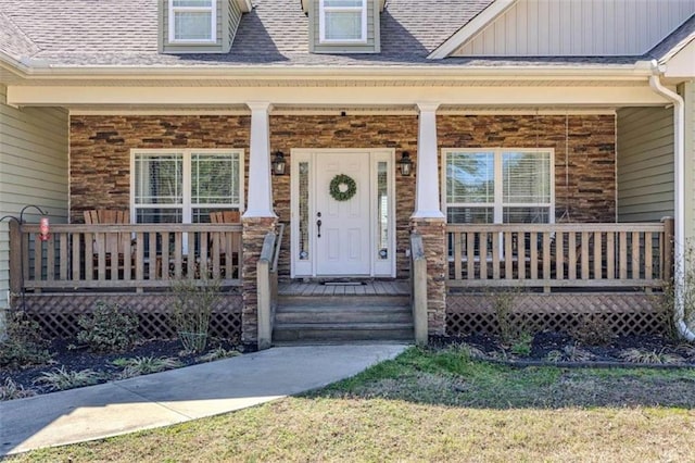 view of exterior entry featuring board and batten siding, brick siding, a porch, and roof with shingles