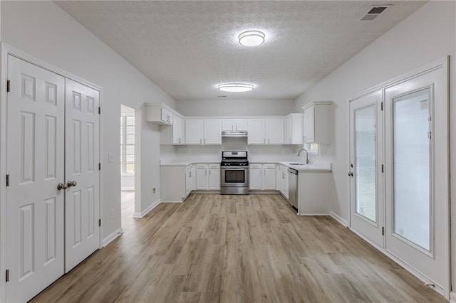 kitchen with light wood finished floors, visible vents, stainless steel appliances, light countertops, and a sink