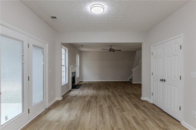 interior space featuring light wood-type flooring, a healthy amount of sunlight, stairway, and a fireplace with raised hearth