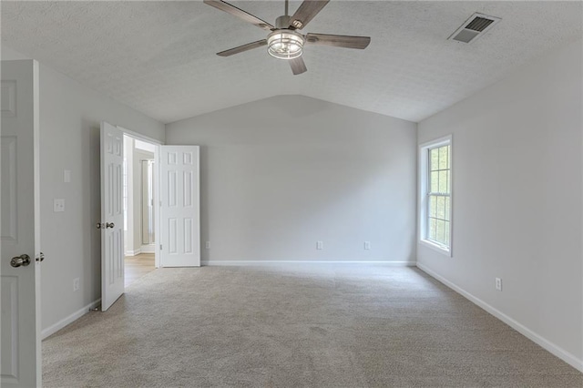 unfurnished room with visible vents, light carpet, vaulted ceiling, a textured ceiling, and baseboards