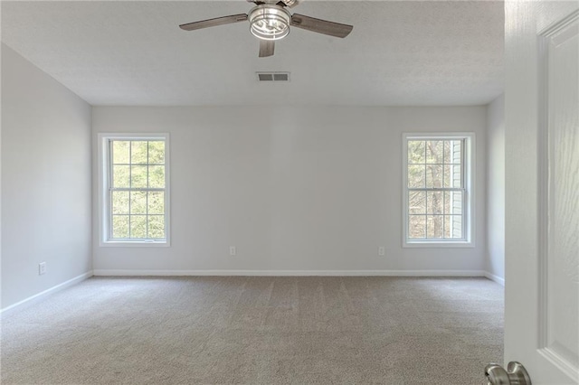 empty room featuring carpet floors, baseboards, visible vents, and a ceiling fan