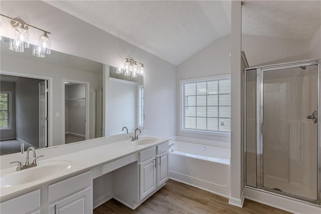 bathroom featuring lofted ceiling, wood finished floors, a stall shower, and a sink