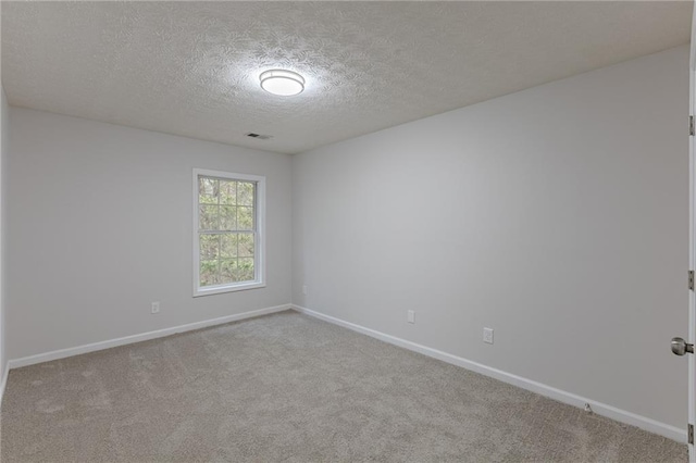 empty room featuring baseboards, a textured ceiling, visible vents, and carpet flooring