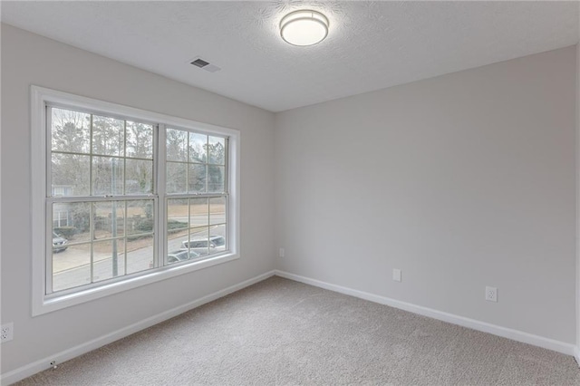 spare room with baseboards, a textured ceiling, visible vents, and carpet flooring