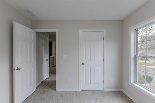 unfurnished bedroom with carpet, visible vents, and baseboards