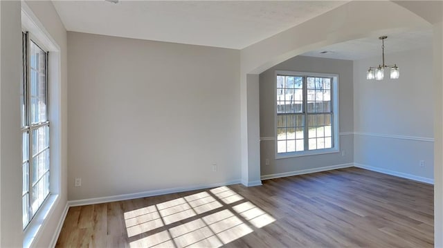 spare room with an inviting chandelier and light wood-type flooring