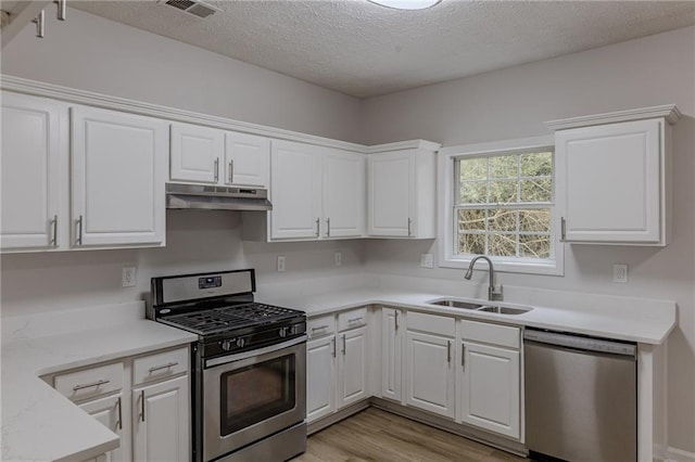 kitchen with under cabinet range hood, stainless steel appliances, a sink, visible vents, and white cabinets