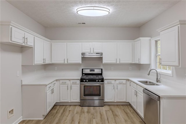 kitchen featuring white cabinets, light wood-style floors, stainless steel appliances, under cabinet range hood, and a sink