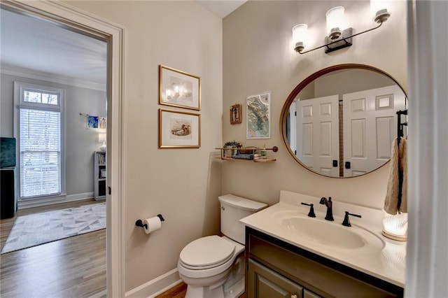 bathroom featuring crown molding, toilet, vanity, wood finished floors, and baseboards