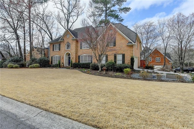 colonial-style house featuring brick siding and a front yard