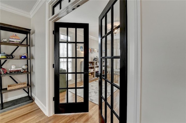 doorway with light wood-style floors, baseboards, ornamental molding, and french doors