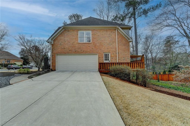 view of side of home featuring concrete driveway, brick siding, fence, and an attached garage