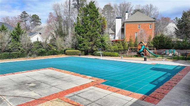 view of swimming pool with a covered pool, a playground, and a patio