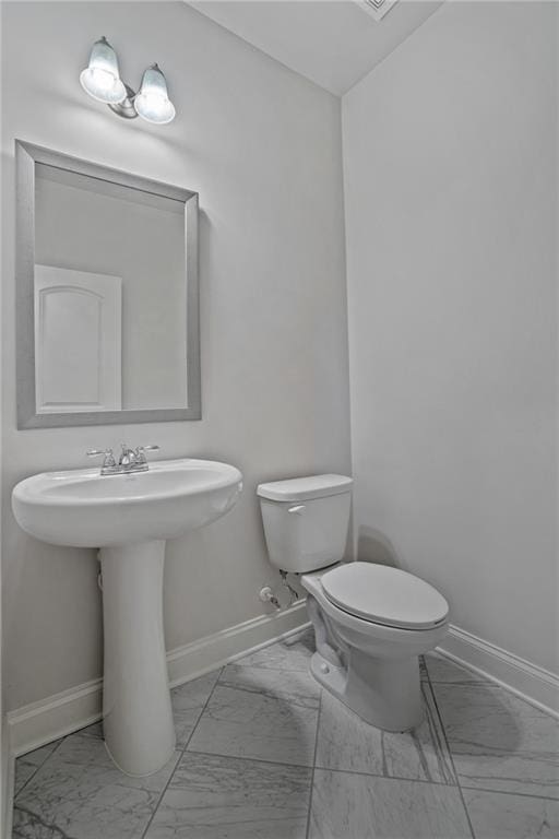 bathroom with baseboards, marble finish floor, and toilet