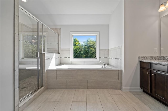 bathroom with a stall shower, vanity, and a bath