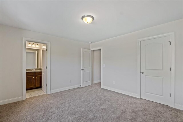 unfurnished bedroom with baseboards, light carpet, and connected bathroom