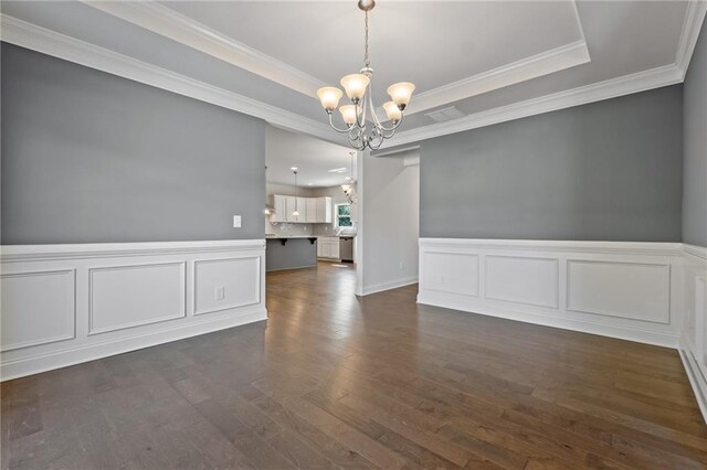 unfurnished dining area featuring a chandelier, ornamental molding, a decorative wall, and dark wood finished floors
