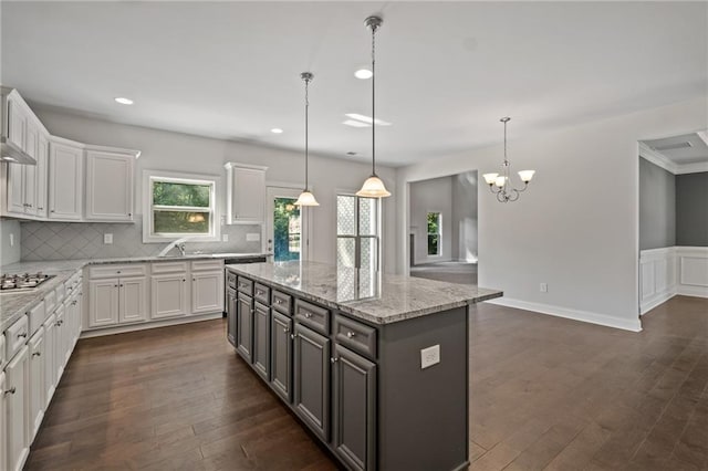 kitchen with backsplash, a center island, white cabinets, and stainless steel gas stovetop