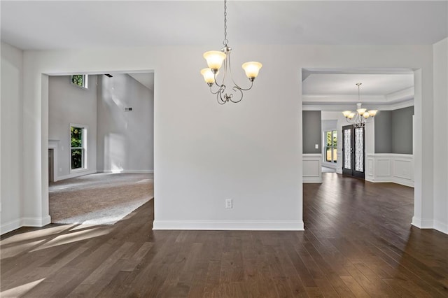unfurnished dining area with an inviting chandelier, dark wood-style flooring, and baseboards