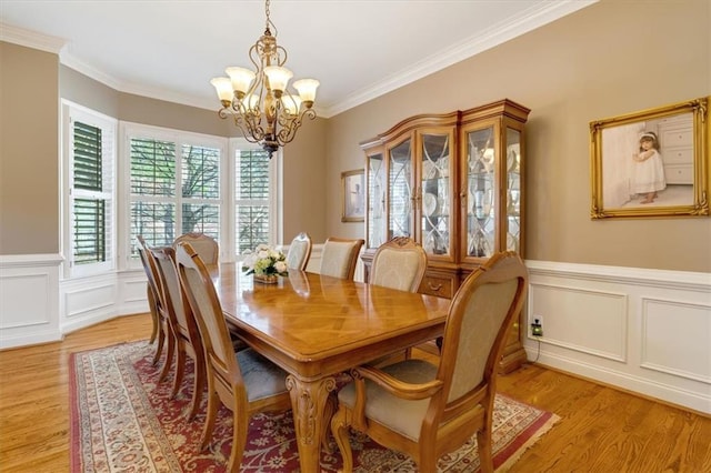 dining room featuring an inviting chandelier, crown molding, and light wood finished floors