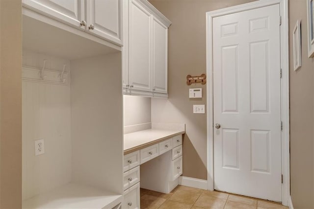 interior space featuring light tile patterned floors, built in desk, and baseboards