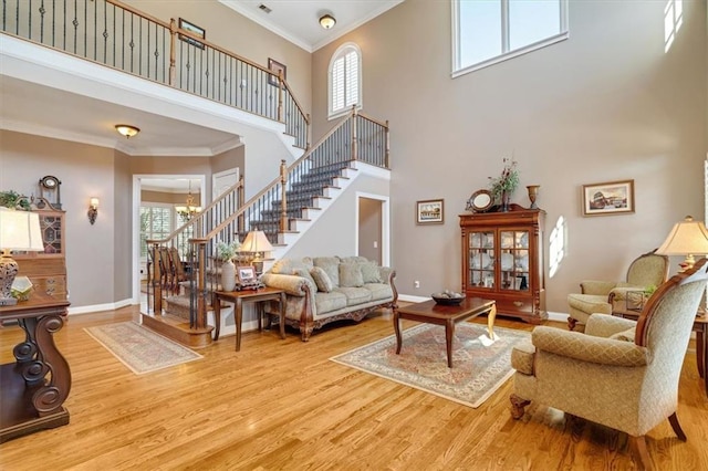 living area featuring wood finished floors, baseboards, stairs, crown molding, and a notable chandelier