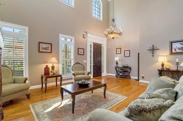 living room featuring light wood-type flooring, baseboards, a healthy amount of sunlight, and a chandelier