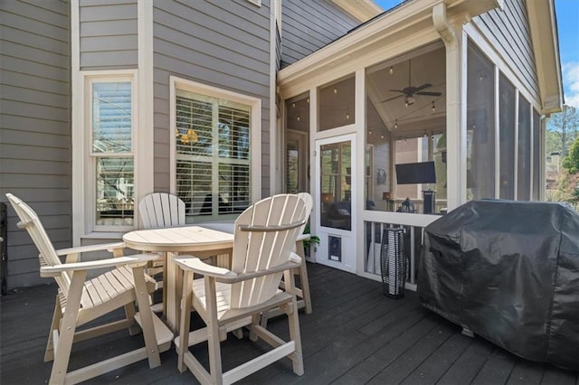 deck with grilling area, outdoor dining area, and a sunroom