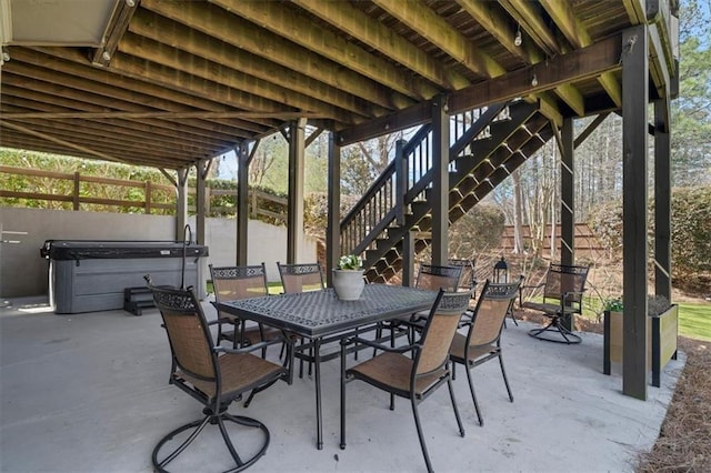 view of patio with stairway, a hot tub, and outdoor dining area