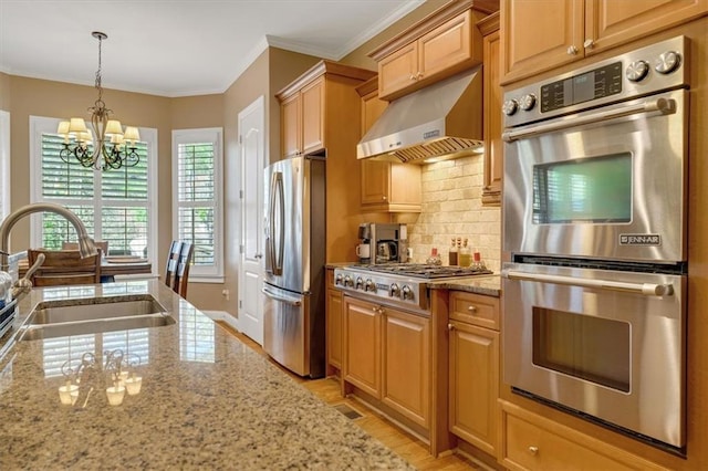 kitchen with under cabinet range hood, a sink, appliances with stainless steel finishes, crown molding, and a chandelier