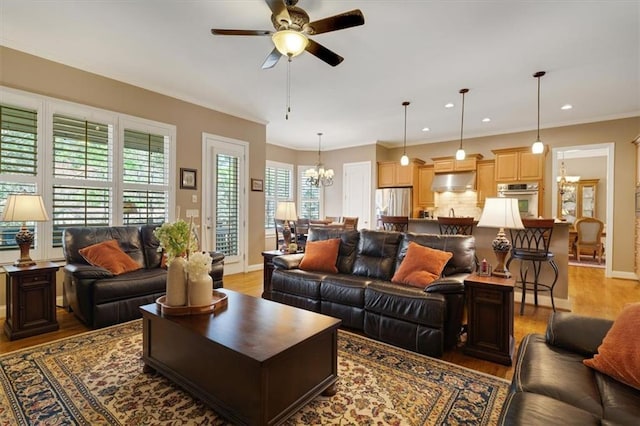 living room with ceiling fan with notable chandelier, baseboards, light wood-style floors, and ornamental molding