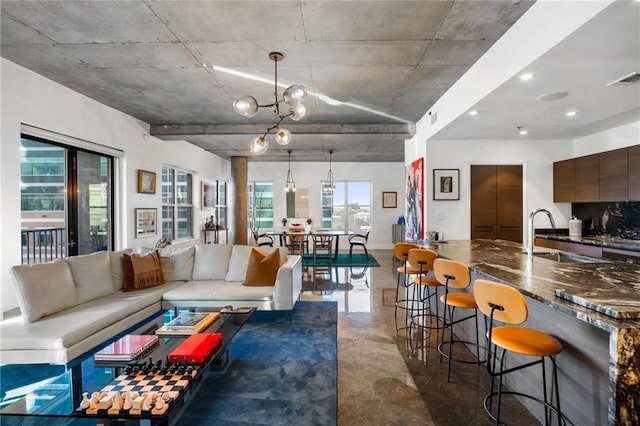 living area featuring concrete flooring, a notable chandelier, plenty of natural light, and visible vents