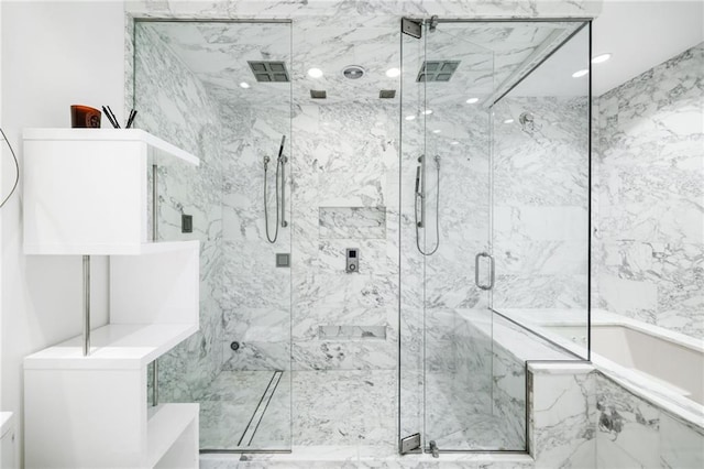 bathroom featuring a marble finish shower and a bath