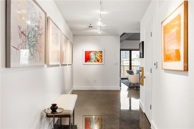 hallway with baseboards, rail lighting, and finished concrete floors