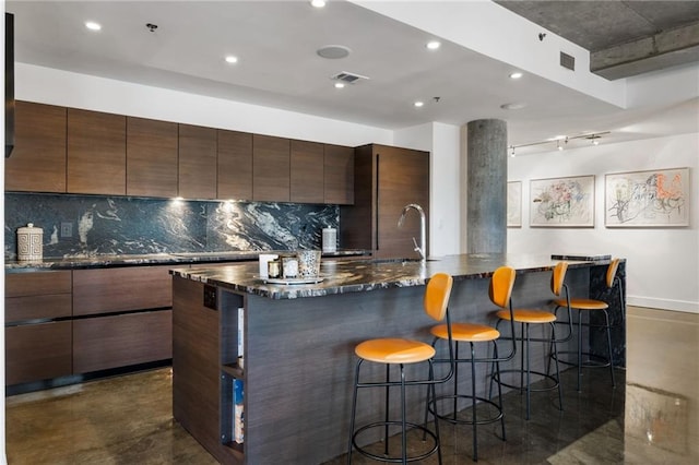 kitchen with finished concrete flooring, a breakfast bar, modern cabinets, and decorative backsplash