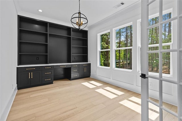 unfurnished office with a notable chandelier, visible vents, built in shelves, and light wood-style flooring