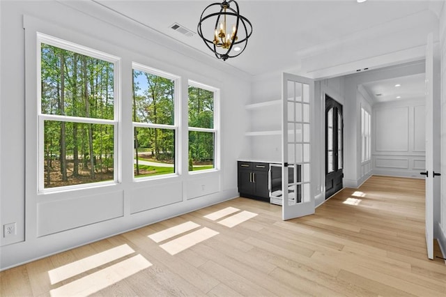 unfurnished dining area featuring a chandelier, visible vents, french doors, and light wood-type flooring