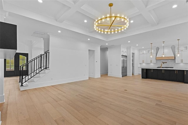 unfurnished living room with baseboards, a chandelier, light wood-style flooring, and coffered ceiling