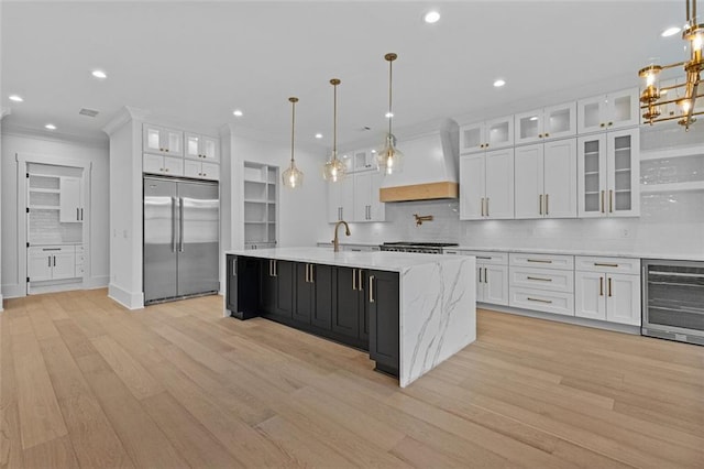 kitchen featuring custom exhaust hood, beverage cooler, white cabinetry, built in fridge, and light wood-style flooring