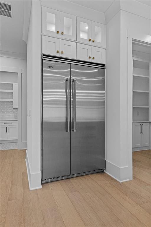 kitchen with visible vents, white cabinets, light wood finished floors, and built in fridge