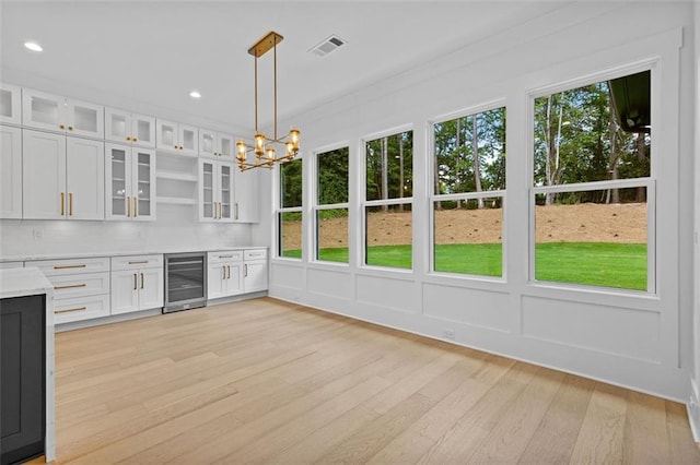 kitchen with light wood-style floors, light countertops, white cabinetry, wine cooler, and visible vents