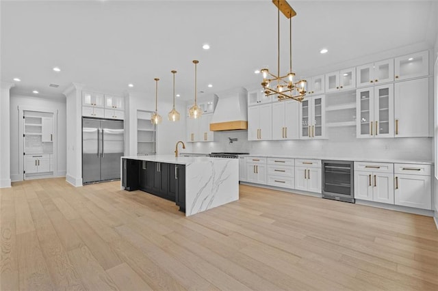 kitchen with white cabinets, beverage cooler, decorative backsplash, custom exhaust hood, and stainless steel built in refrigerator