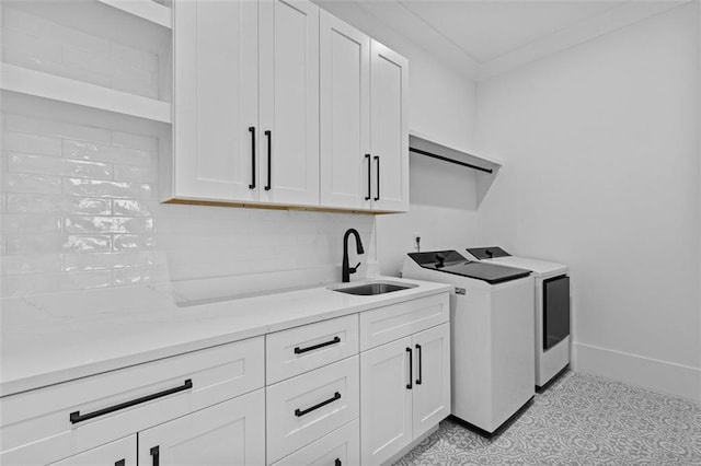 clothes washing area with washing machine and clothes dryer, cabinet space, a sink, baseboards, and light floors