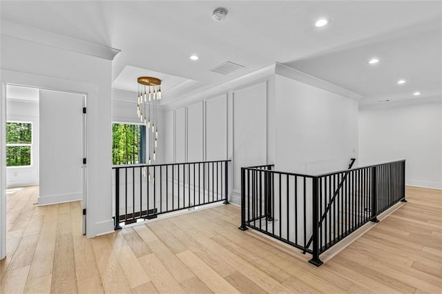 hall with visible vents, wood finished floors, baseboards, an upstairs landing, and recessed lighting